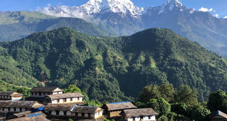 Bergdorf mit traditionellen Gebäuden und grünen Hügeln.