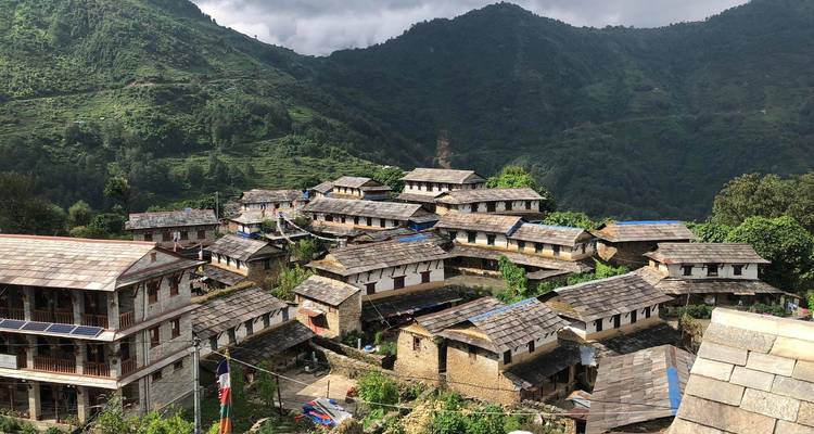 Traditionelles Bergdorf mit umliegenden grünen Hügeln.
