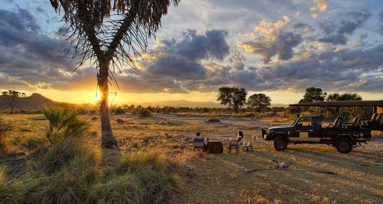 Safari-Landschaft mit Menschen, die den Sonnenuntergang in einer Savannenumgebung genießen.