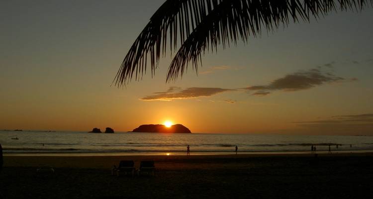 Een prachtige zonsondergang boven de oceaan met silhouetten van mensen op het strand.