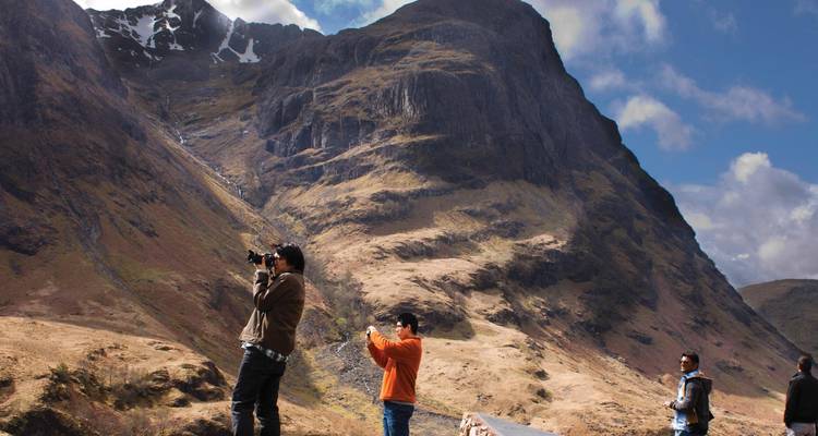 Les voyageurs photographient des montagnes spectaculaires et des vallées partiellement enneigées à Glencoe.