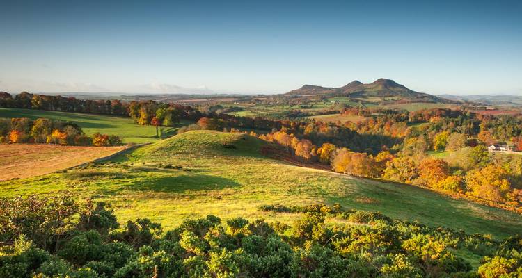 Campiña otoñal ondulante con campos de retazos y dos colinas gemelas bajo un cielo despejado.