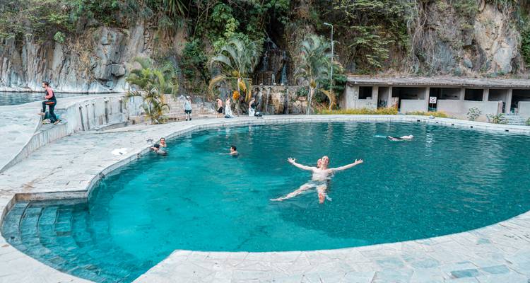 Personas nadando en una piscina natural en una zona montañosa.