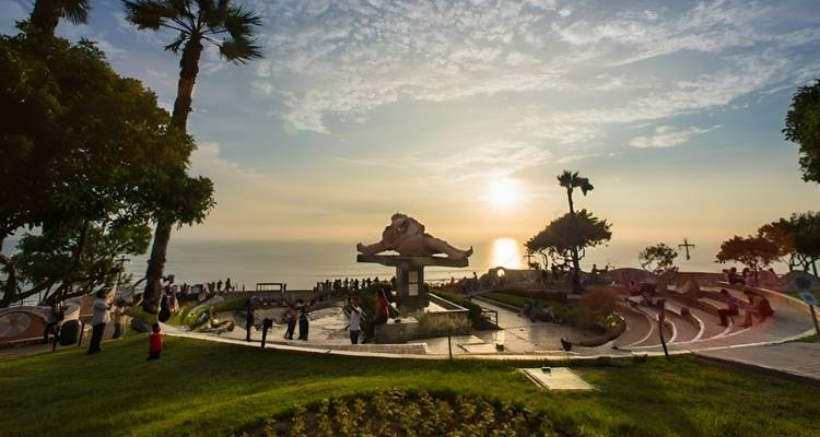 Parque con una escultura al atardecer, con vista al océano.