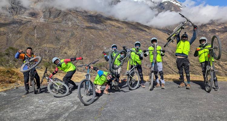 Grupo de ciclistas posando con entusiasmo con sus bicicletas en una región montañosa.