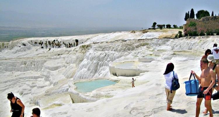Touristen erkunden die berühmten weißen Terrassen von Pamukkale.