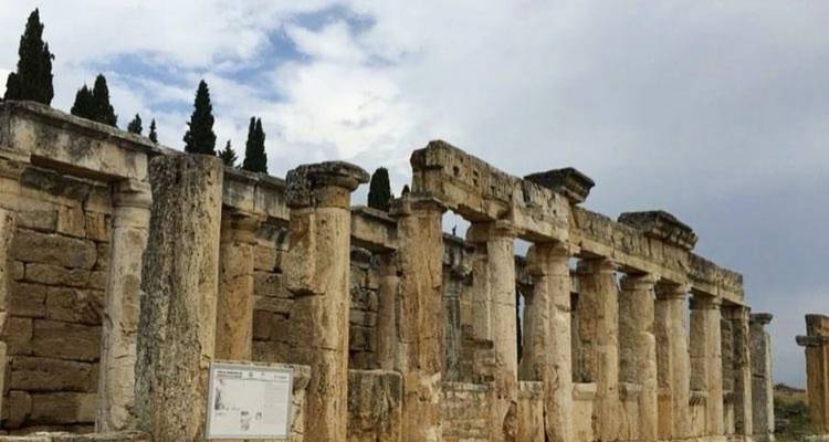 Ruinas romanas antiguas con columnas bajo un cielo nublado.