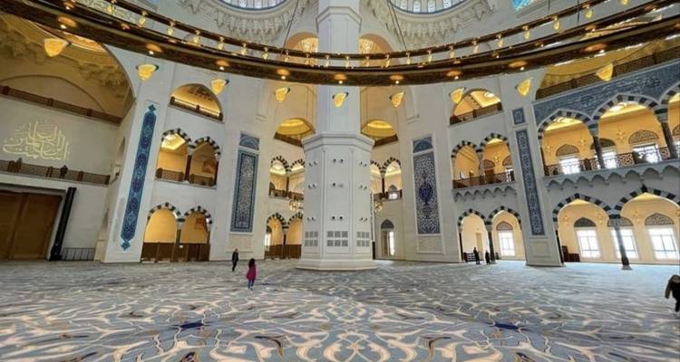 Intérieur spacieux d'une mosquée aux motifs complexes.