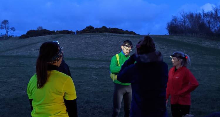 Night scene with people wearing headlamps on a grassy area.