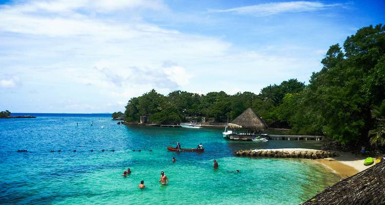 Des touristes nagent et se détendent dans une eau turquoise claire.