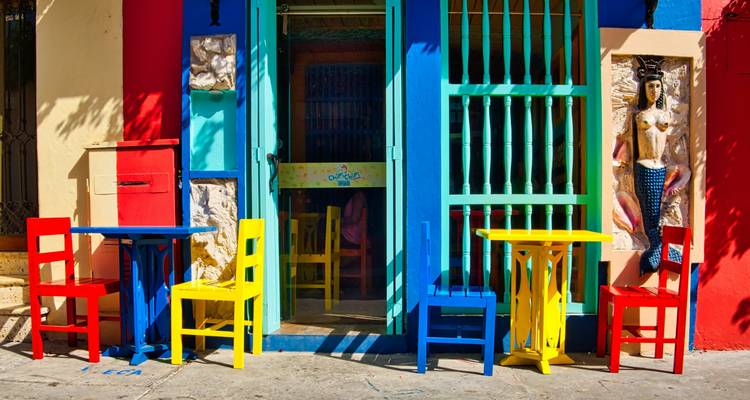 Chaises et tables colorées à l'extérieur d'un café vibrant.