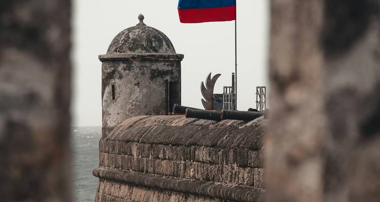 Forteresse historique avec drapeau et vue sur mer.