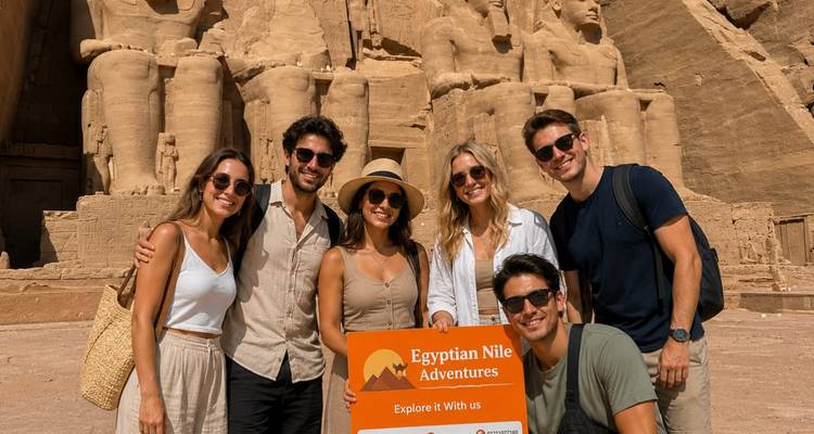 Los viajeros posan con un letrero antes de las colosales estatuas sentadas talladas en la fachada del templo de Abu Simbel.