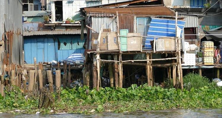 Ein Cluster rustikaler Häuser auf Stelzen an einem Fluss.