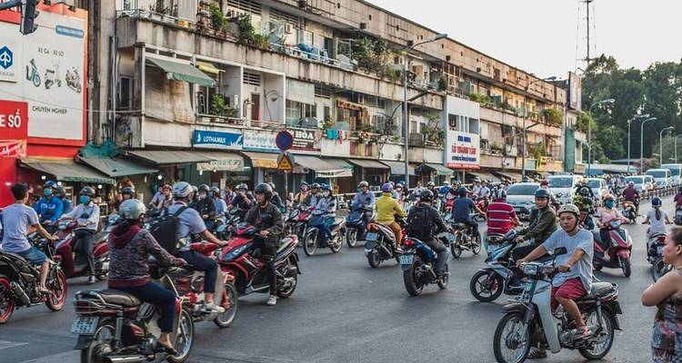 Lebhafte Straßenszene mit zahlreichen Motorrädern und Gebäuden.