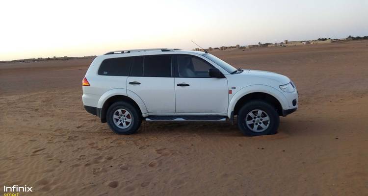 SUV blanc garé sur un terrain sablonneux.