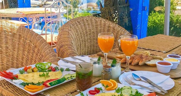 Terrasse de café avec des assiettes de nourriture et des boissons.