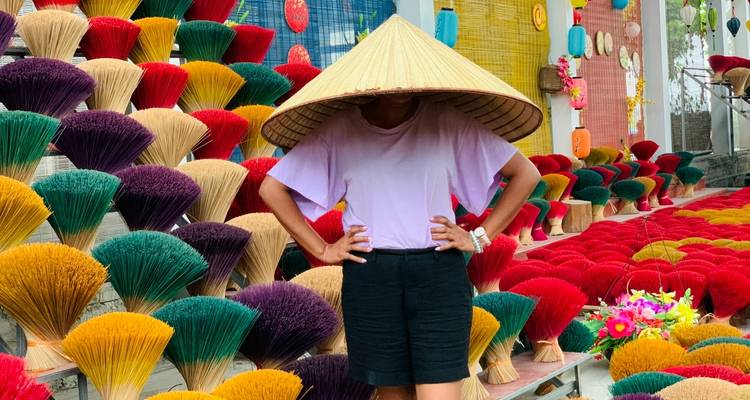 Person mit einem großen Hut zwischen bunten Räucherstäbchen.