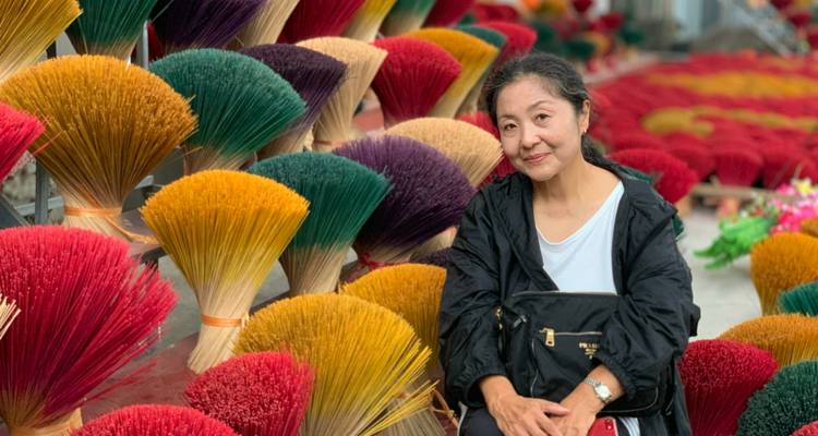 Frau sitzt zwischen bunten gebündelten Räucherstäbchen.