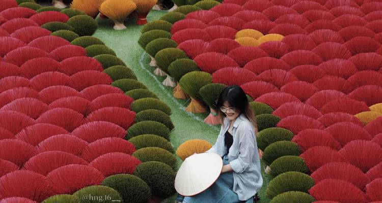 Person zwischen kunstvoll arrangierten Räucherstäbchen.