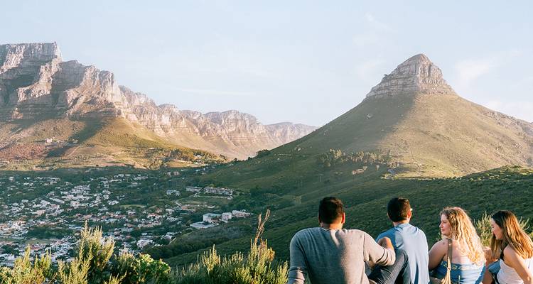 Los viajeros descansan en una ladera con vista a Ciudad del Cabo con Lion's Head y Table Mountain a la vista.