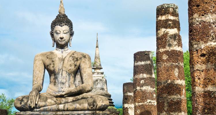 Groot zittend Boeddhabeeld tussen de ruïnes van een oude tempel in Sukhothai.