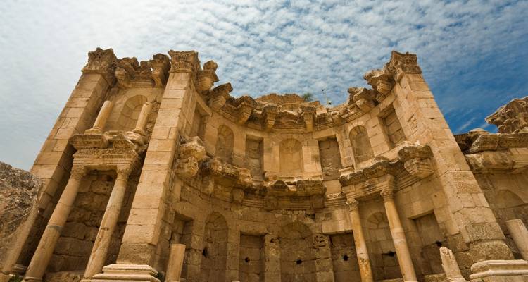 Ruinas de piedra del Ninfeo de Jerash capturadas desde abajo con nubes con patrón arriba.