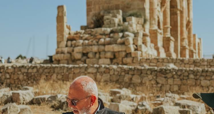 Guía con gafas de sol habla en las ruinas antiguas de la colina con el templo borroso de fondo.