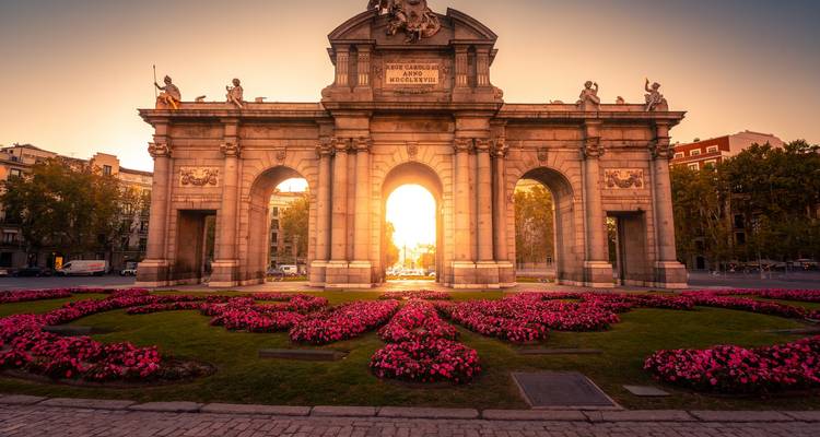Puerta de Alcalá au coucher du soleil, entourée d'un jardin de fleurs