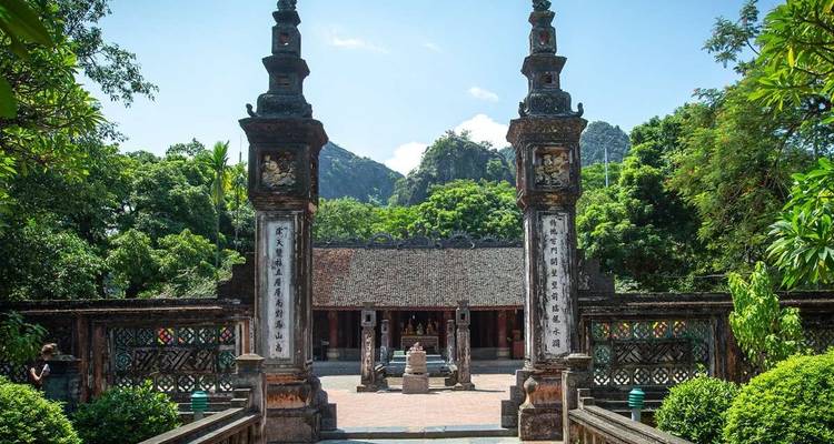 Entrée de temple traditionnel avec des arbres verts luxuriants.