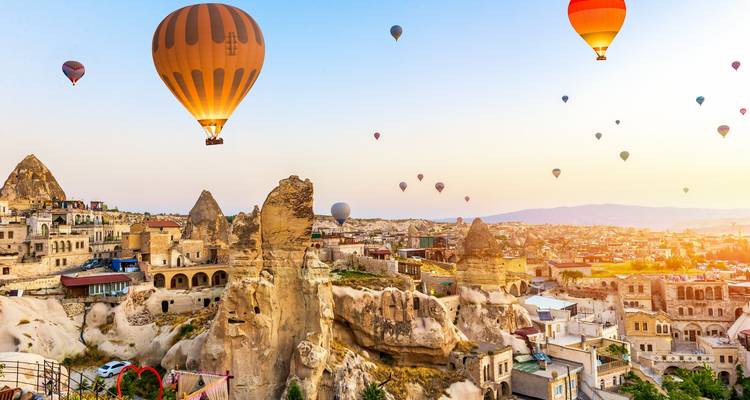 Scenic view of hot air balloons over a rock formation town.