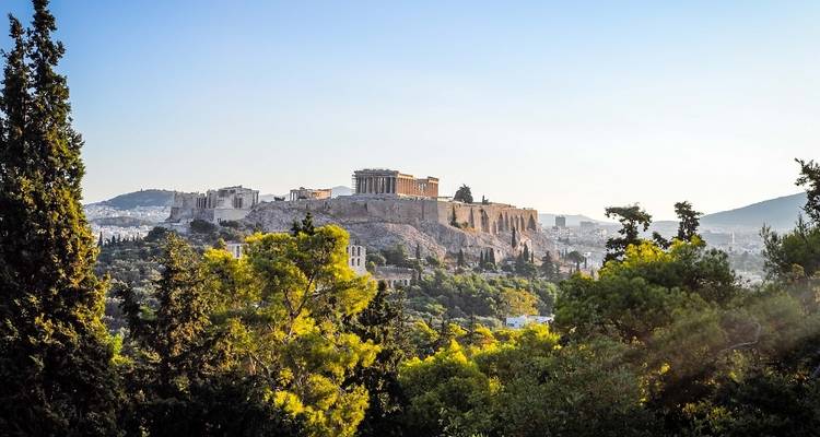 Blick auf die Akropolis, umgeben von grünen Bäumen und blauem Himmel.