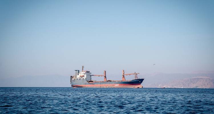 Ein großes Frachtschiff, das auf dem Meer segelt, mit fernen Hügeln.