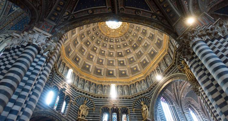 Innenraum einer Kathedrale mit kunstvoller Kuppel und gestreiften Säulen.