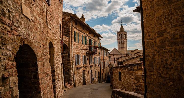 Schmale Kopfsteinpflasterstraße in einer historischen Stadt mit sichtbarem Kirchturm.