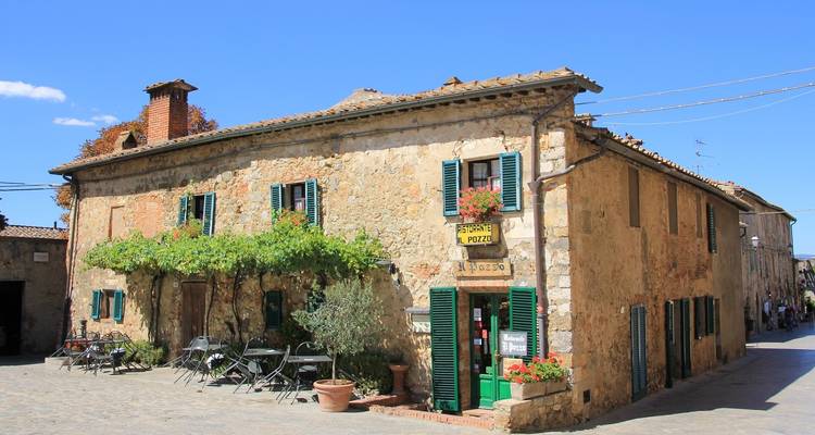 Steinhaus mit grünen Fensterläden und einer kleinen Pizzeria.