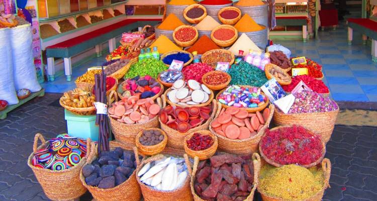 Una exhibición colorida de varias especias y productos en canastas en un mercado local.