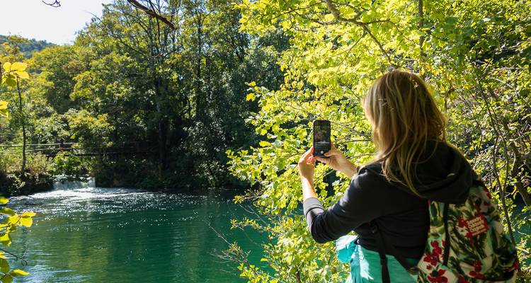 Een persoon die foto's maakt van een schilderachtig gebied met stromend water.