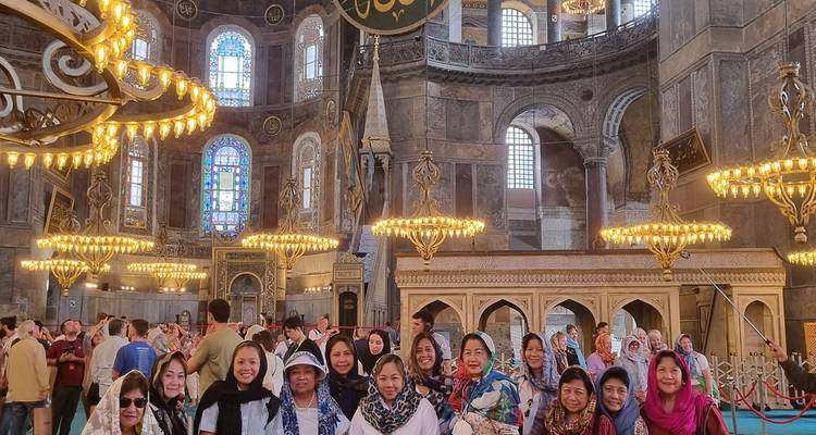 Portrait de groupe à l'intérieur d'une mosquée historique avec vitraux et lustres.