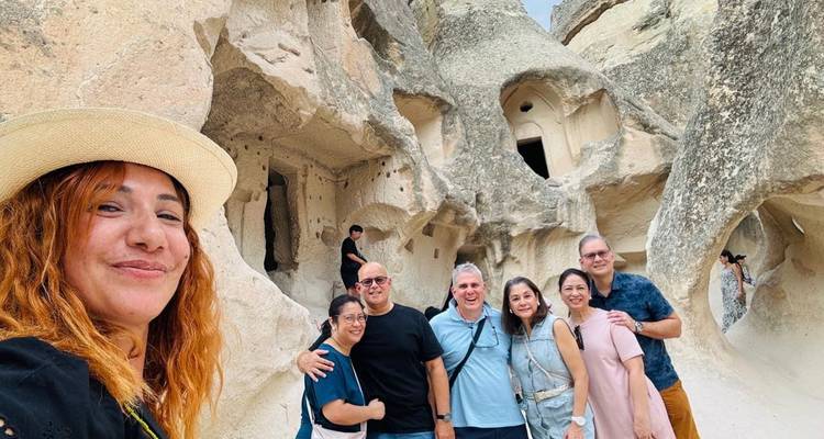 Grupo posando frente a una formación rocosa con viviendas talladas.