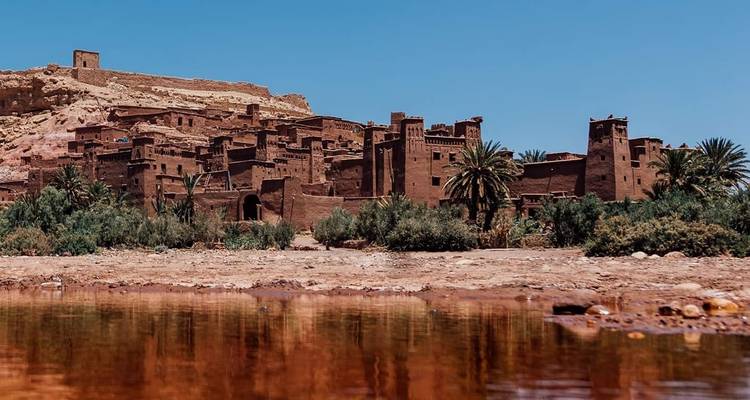 Oud gebouw met leemwanden dat weerkaatst in een wateroppervlak.