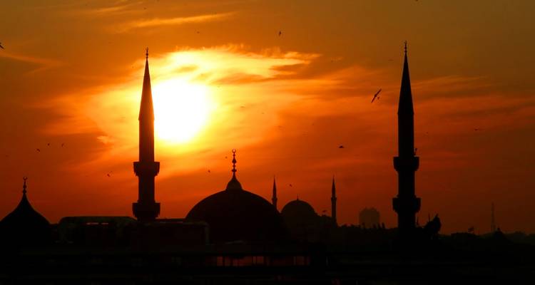 Silhouet van minaretten tegen een zonsonderganghemel