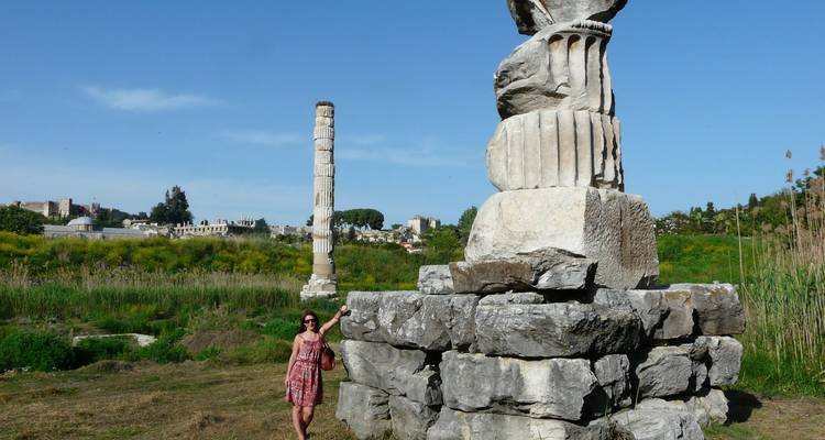 Visitor poses beside the lone column and stone blocks of the Temple of Artemis ruin near Ephesus.