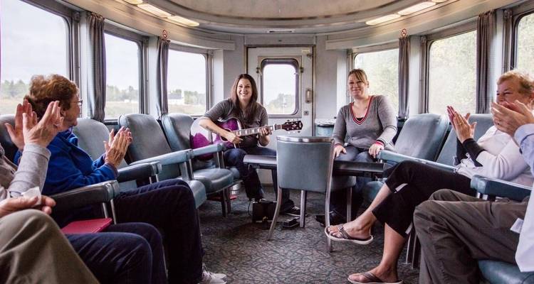Des gens assis jouant de la guitare dans un compartiment de train.