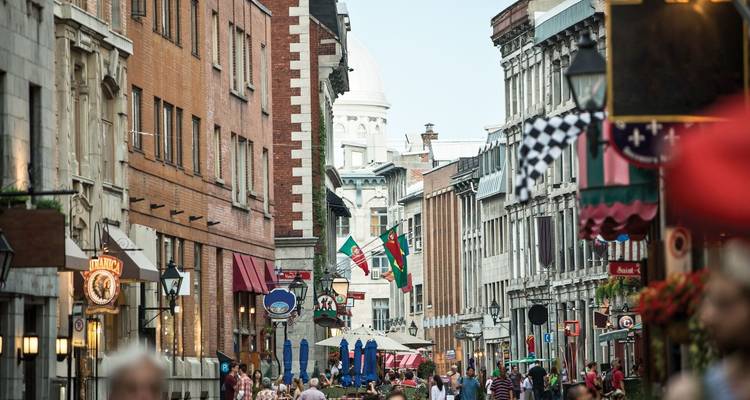 Rue urbaine animée avec des gens, des magasins et des cafés.