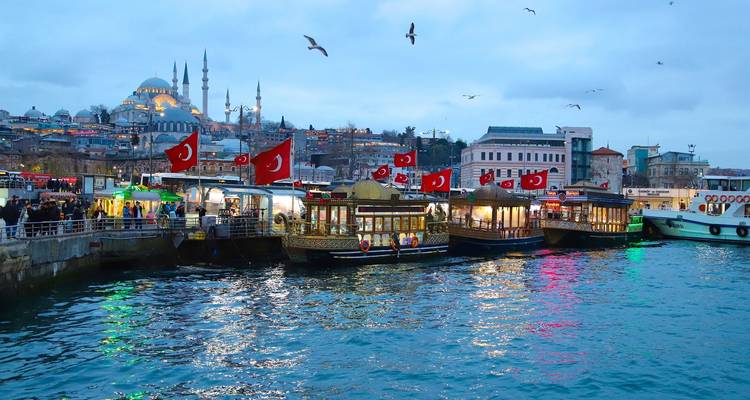 Bosporusscène aan het water met boten en Turkse vlaggen.