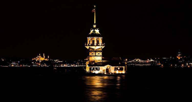 Kızkulesi 's nachts verlicht tegen het water.