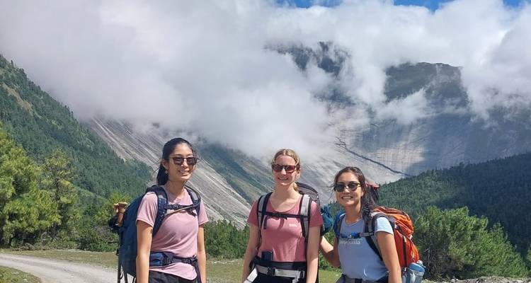 Trois randonneurs posant avec un paysage de montagne en arrière-plan.