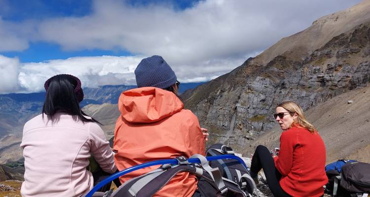 Trois randonneurs assis sur une corniche de montagne avec des sacs à dos.