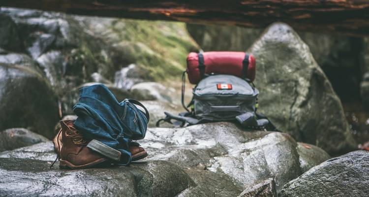 Campingausrüstung auf felsigem Boden in einer Waldumgebung.